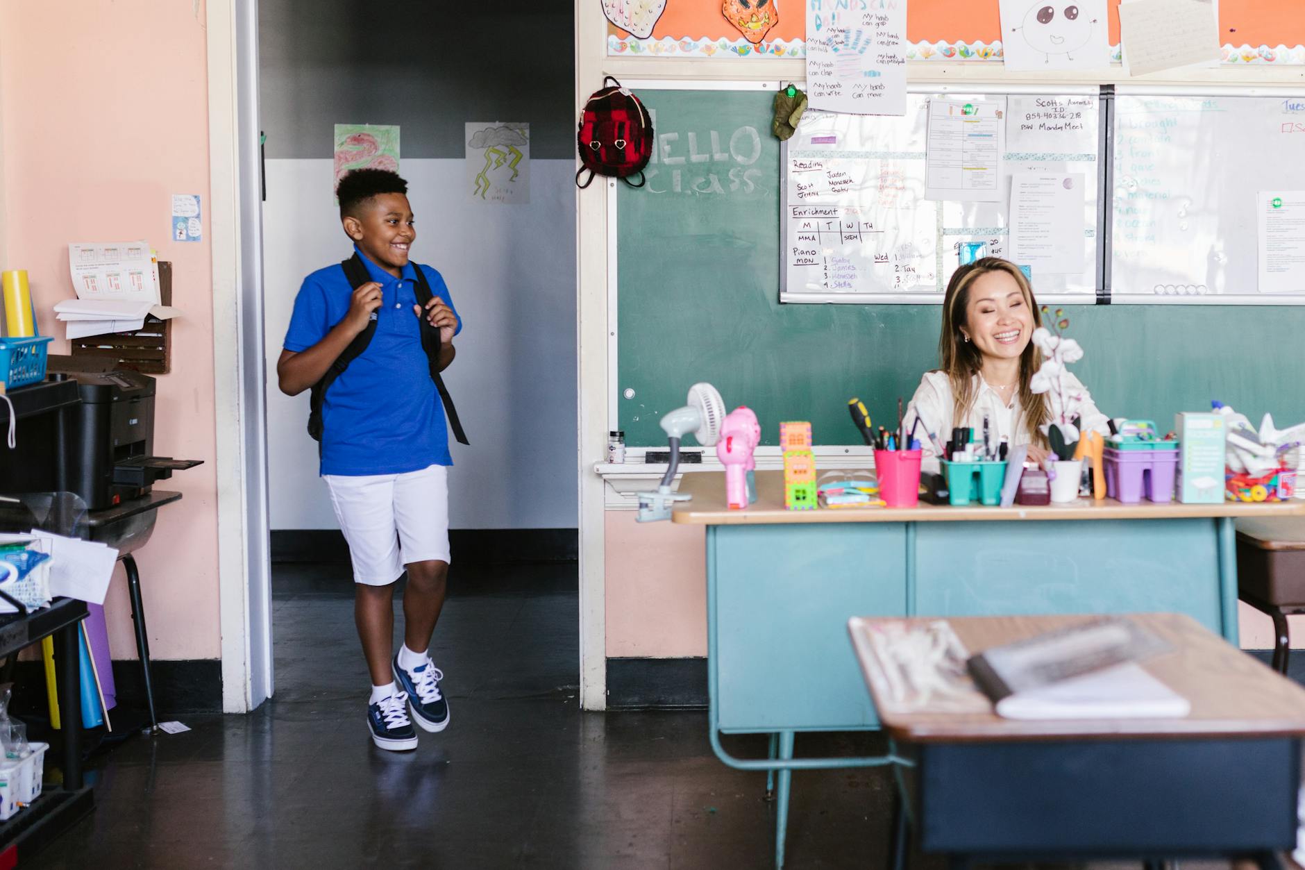 boy in blue shirt with black backpack standing on the doorway